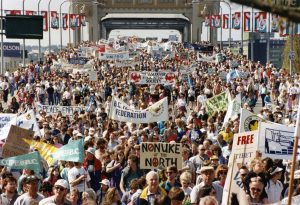 Mass of people with banners and signs, crossing Burrard St. Bridge. VFSS banner is visible!